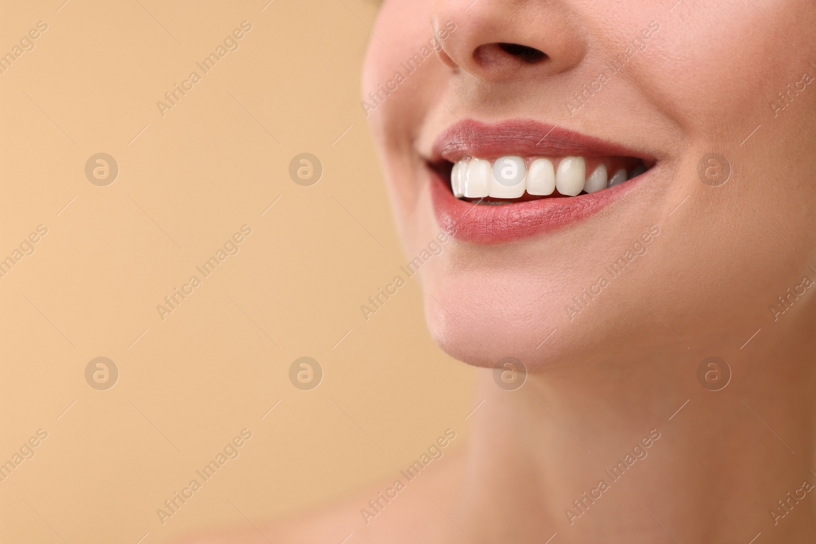 Photo of Woman with beautiful lips smiling on beige background, closeup. Space for text