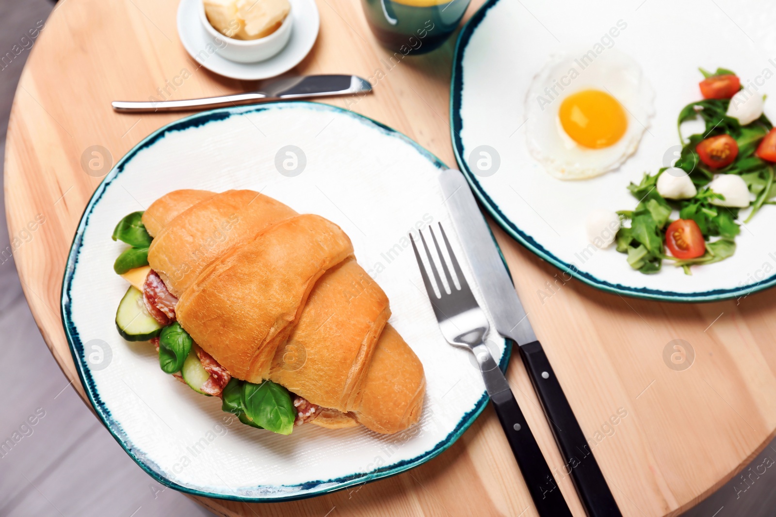 Photo of Tasty croissant sandwich served for breakfast on table