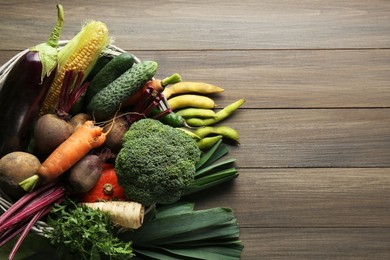 Basket with different fresh ripe vegetables on wooden table, top view. Space for text