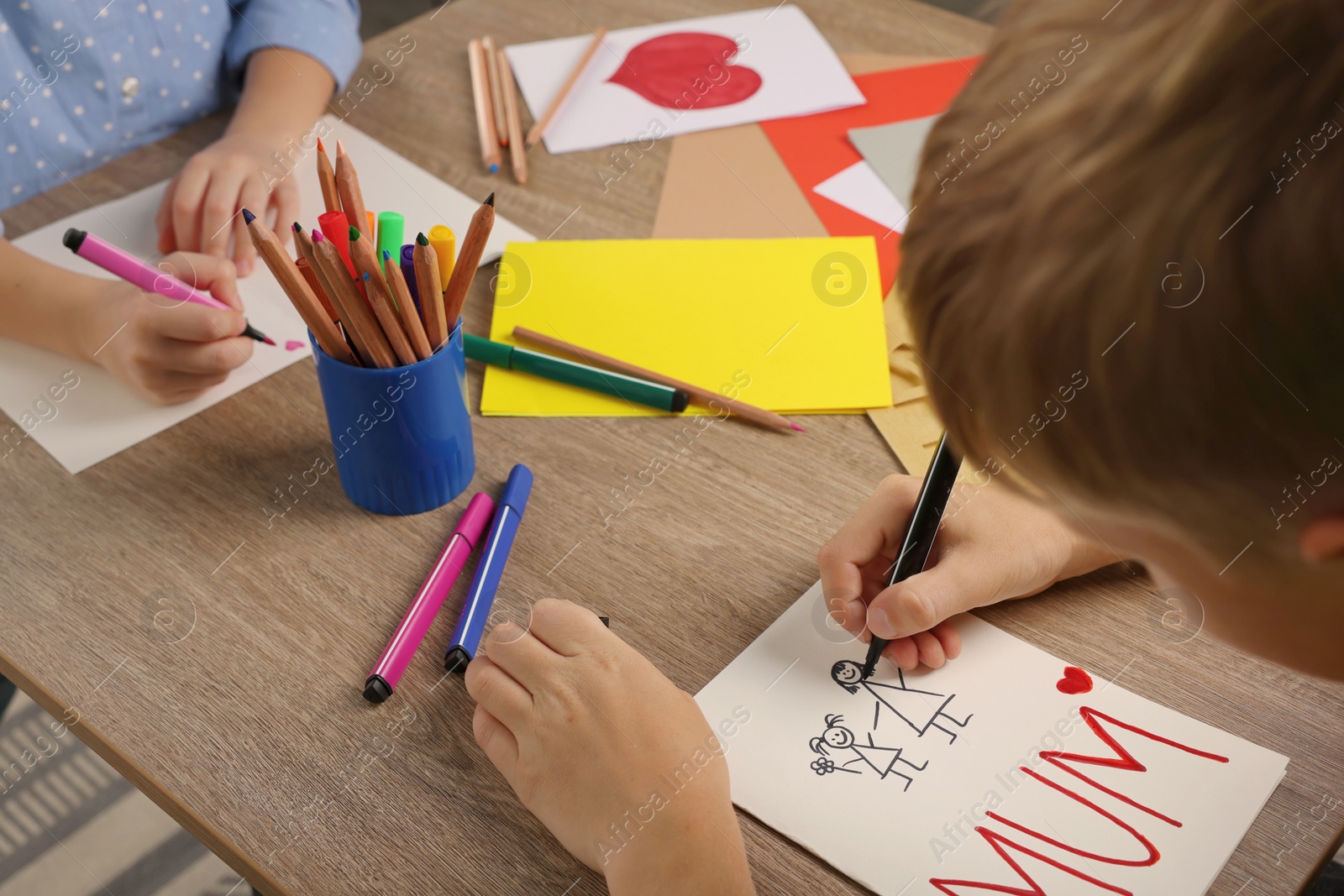 Photo of Children making beautiful greeting cards at table indoors, closeup