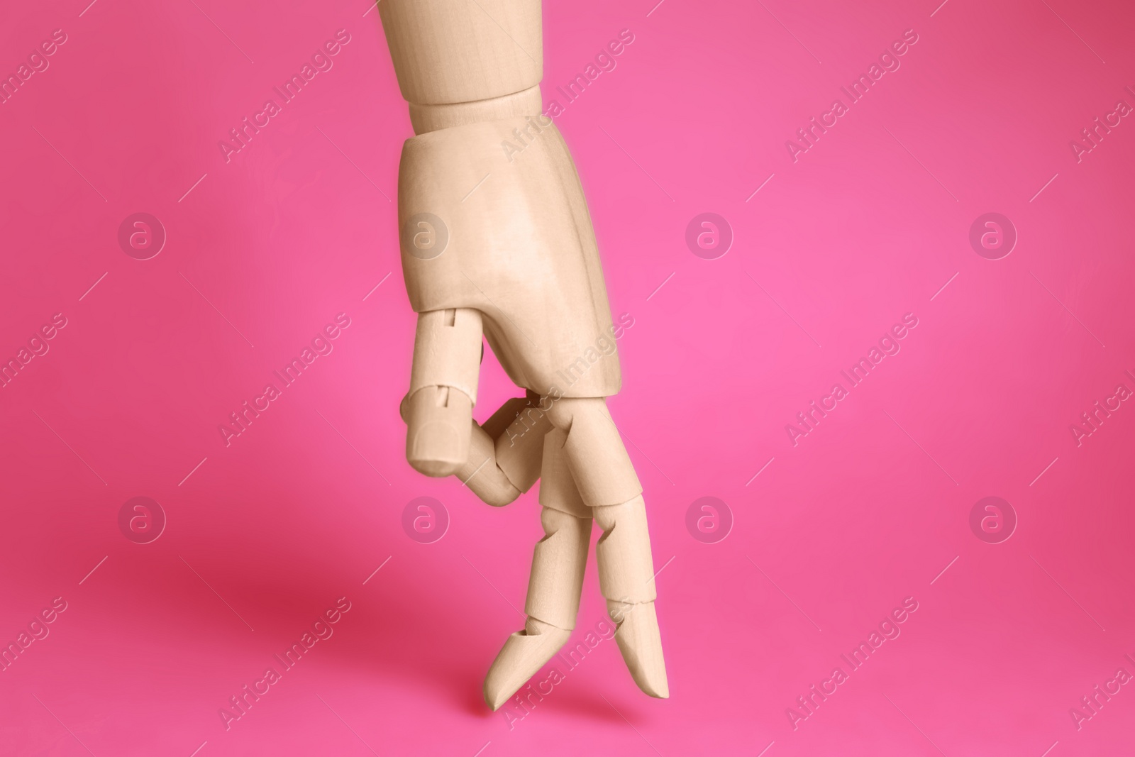 Photo of Wooden hand model on pink background. Mannequin part