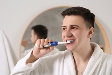 Man brushing his teeth with electric toothbrush in bathroom