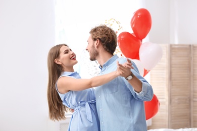 Young couple with air balloons at home. Celebration of Saint Valentine's Day