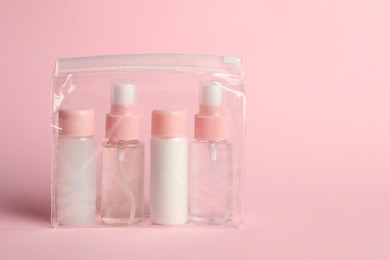 Photo of Cosmetic travel kit in plastic bag on pink background. Space for text