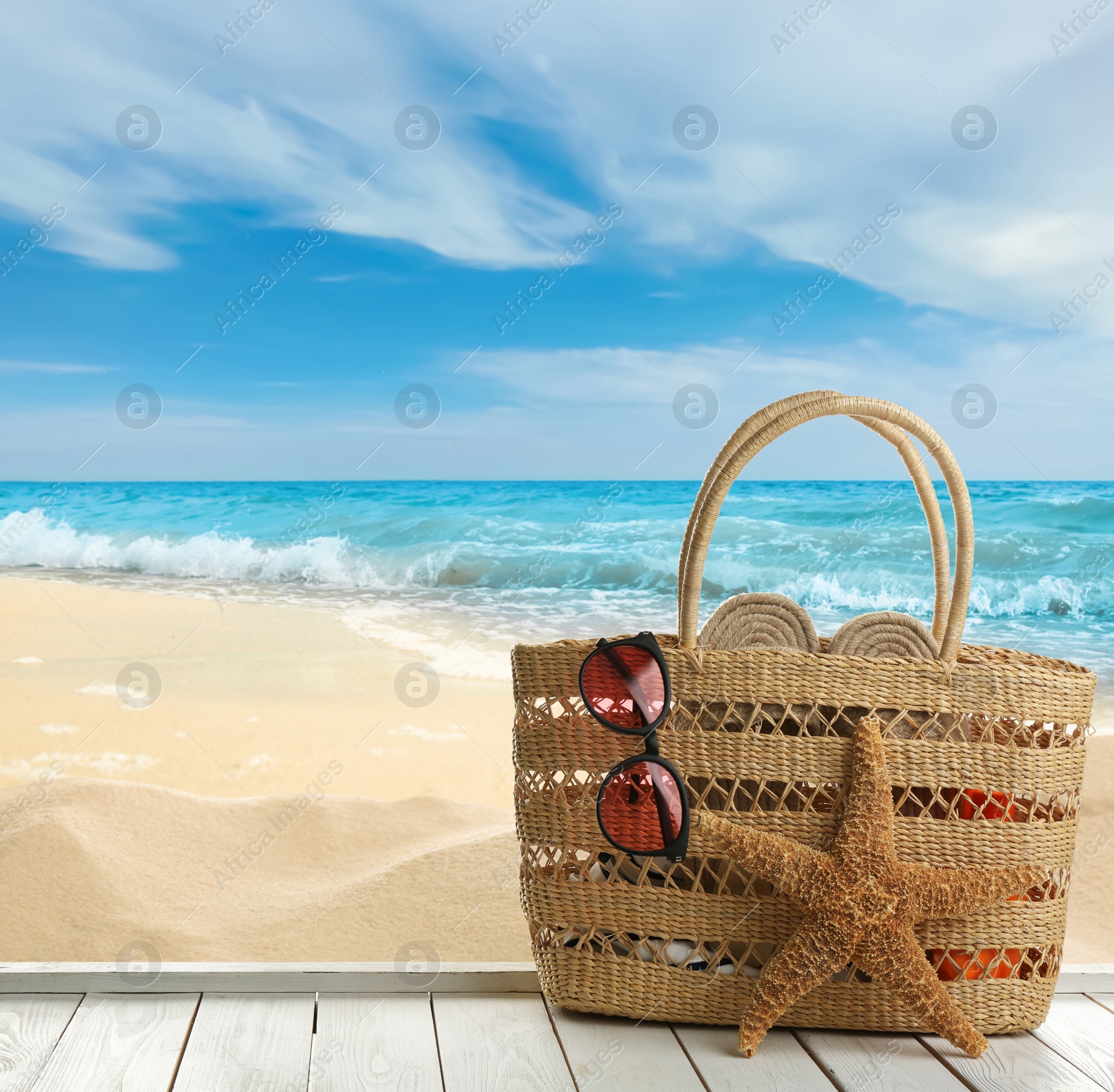 Image of Beach accessories on white wooden surface near ocean, space for text