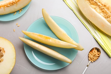 Photo of Slices of delicious honey melon on light grey table, flat lay