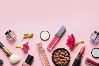 Different makeup products with flowers on color background. Space for text