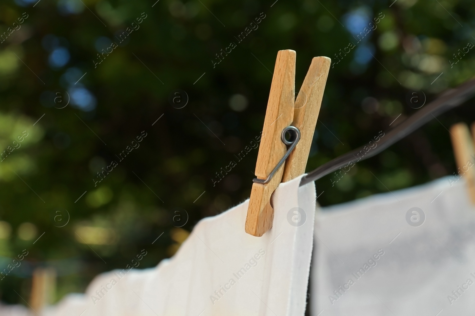 Photo of Washing line with clean laundry and clothespin outdoors, closeup