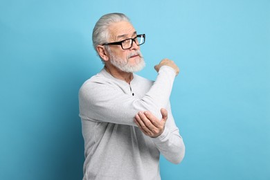 Photo of Arthritis symptoms. Man suffering from pain in elbow on light blue background