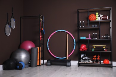 Many different sports equipment in room with brown walls