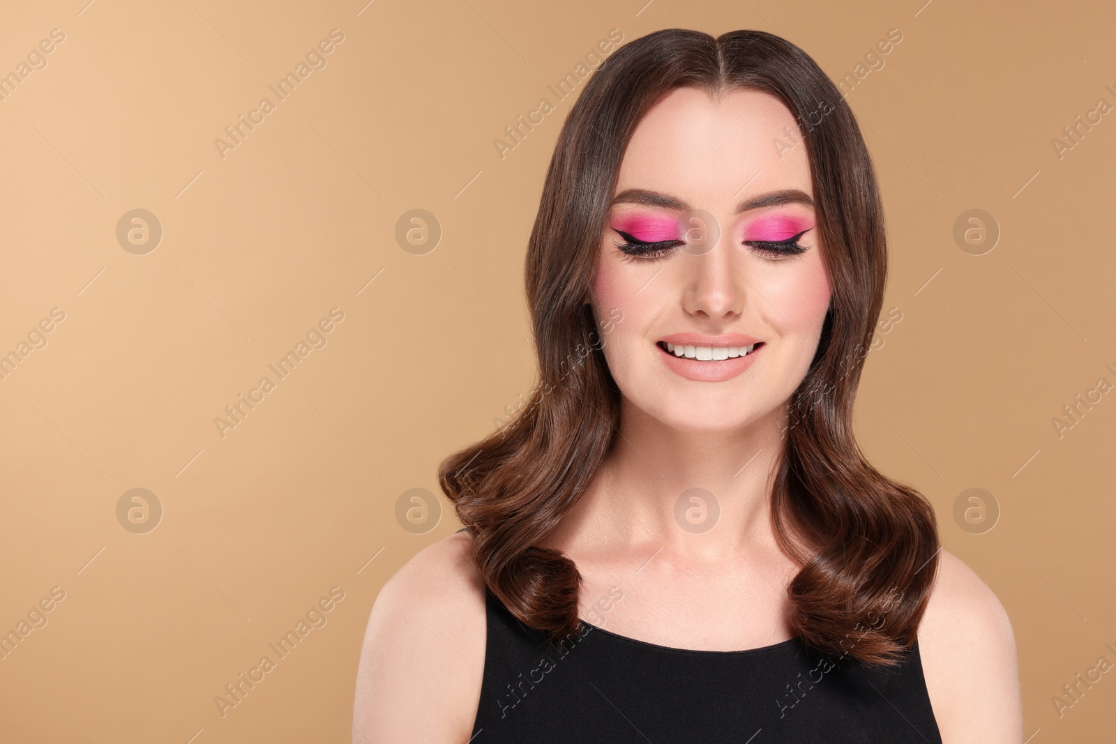 Photo of Portrait of beautiful young woman with makeup and gorgeous hair styling on beige background. Space for text