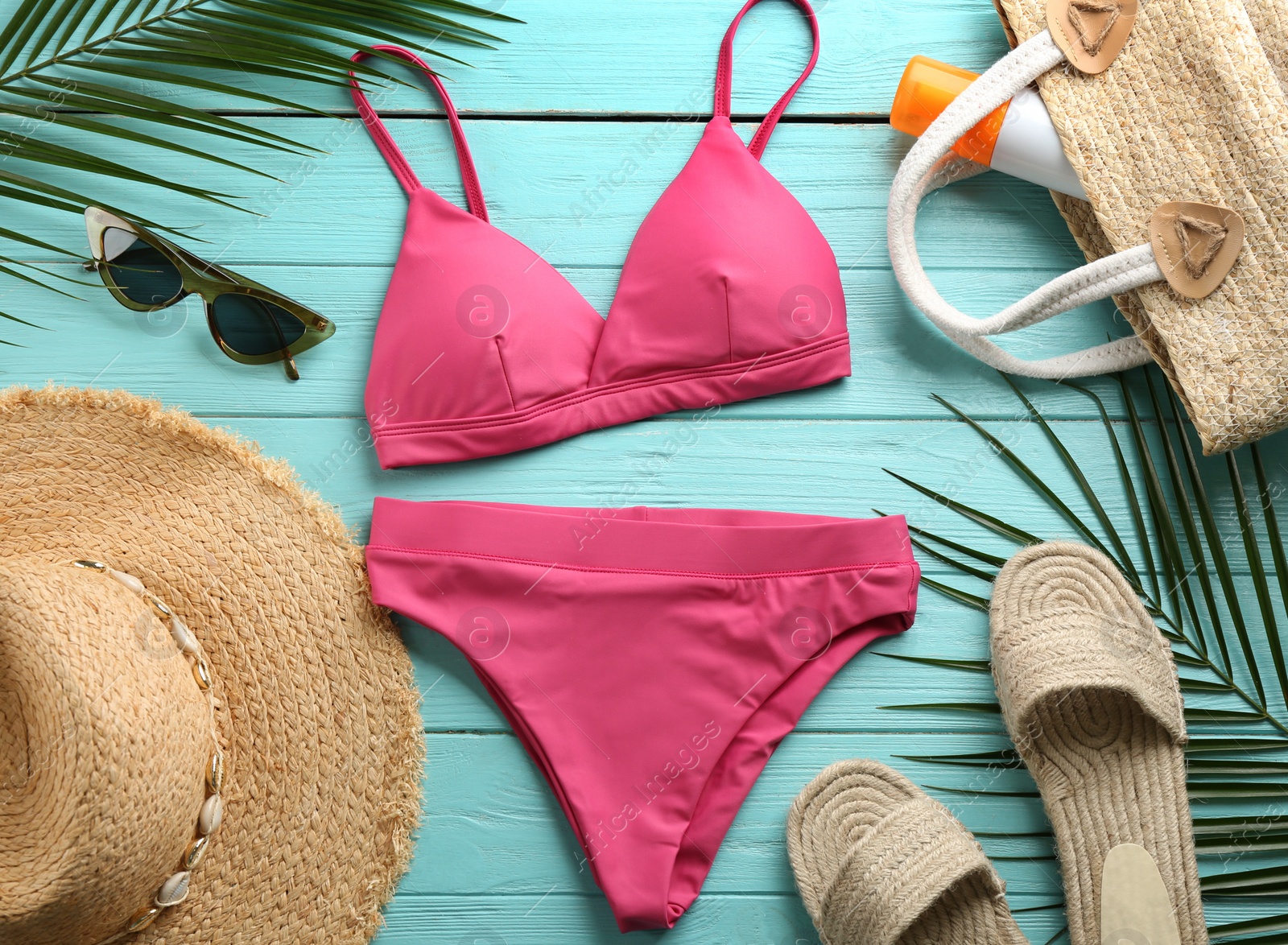 Photo of Beautiful pink bikini and beach accessories on light blue wooden background, flat lay