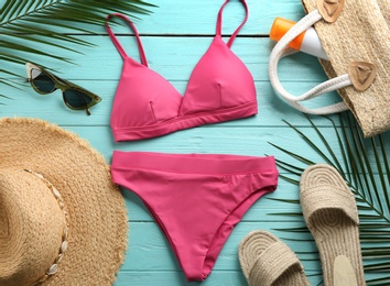 Photo of Beautiful pink bikini and beach accessories on light blue wooden background, flat lay