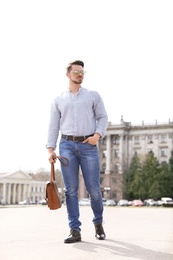 Handsome young man in stylish outfit and leather shoes outdoors