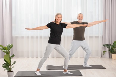 Senior couple practicing yoga on mats at home