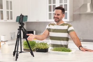 Photo of Teacher with microgreens conducting online course in kitchen. Time for hobby