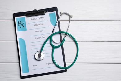 Clipboard with medical prescription form and stethoscope on white wooden table, flat lay. Space for text