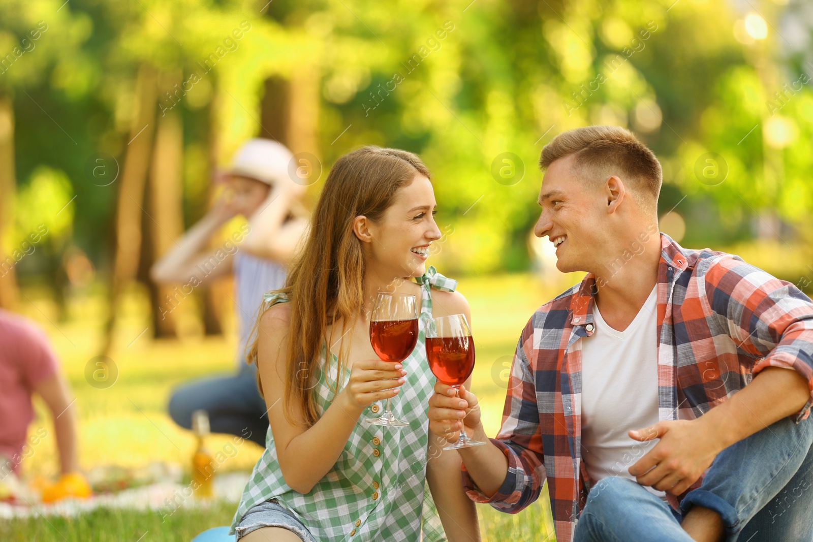 Photo of Young couple enjoying picnic in park on summer day