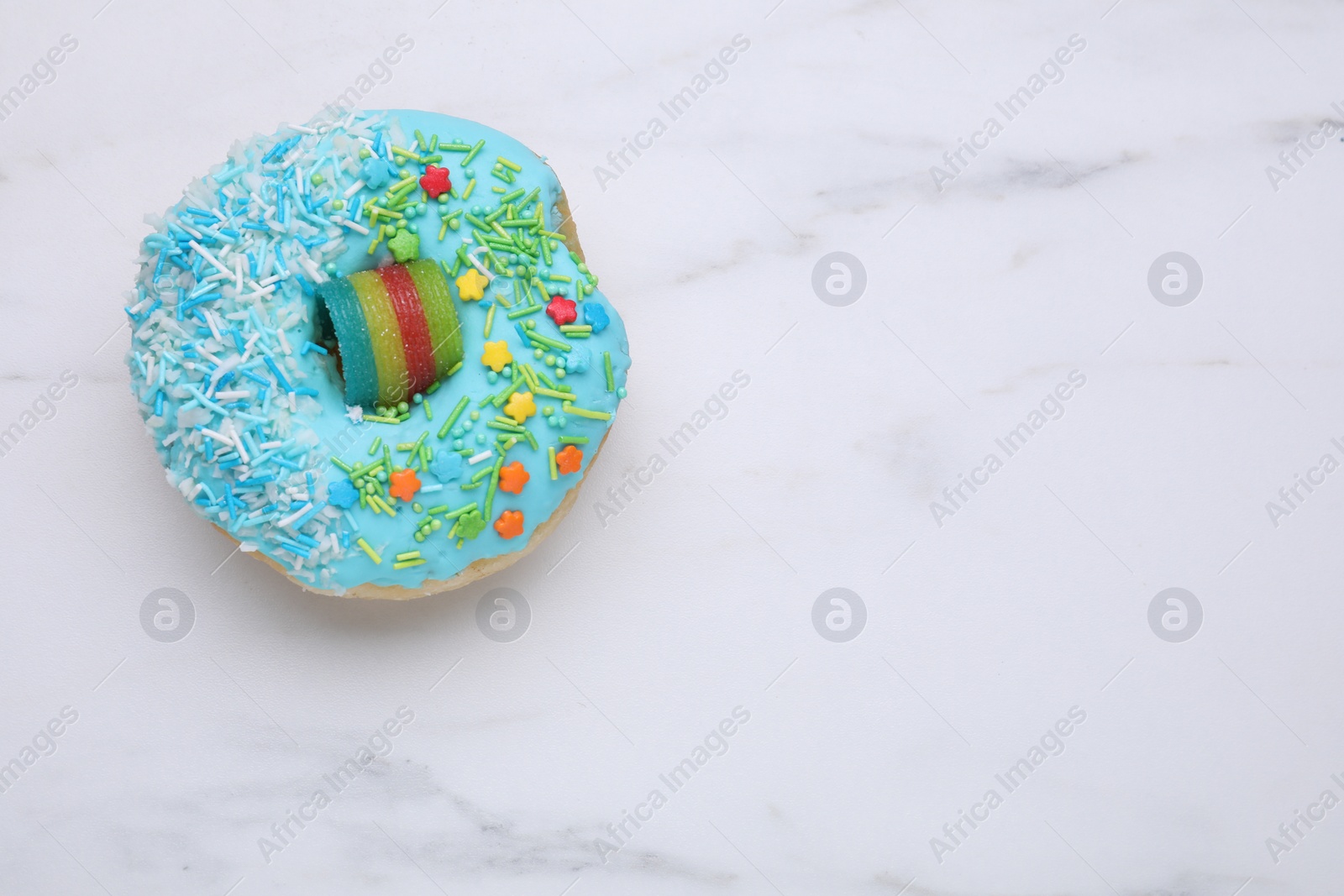 Photo of Sweet glazed donut decorated with sprinkles on white marble table, top view and space for text. Tasty confectionery