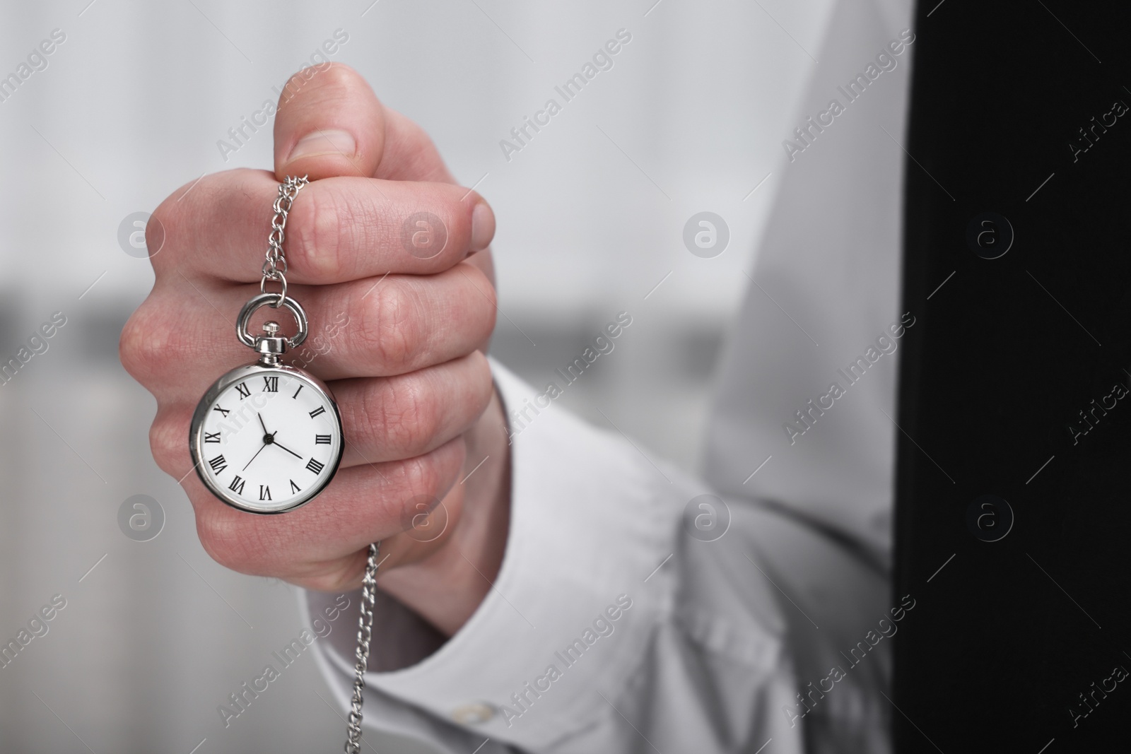 Photo of Man holding chain with elegant pocket watch on blurred background, closeup