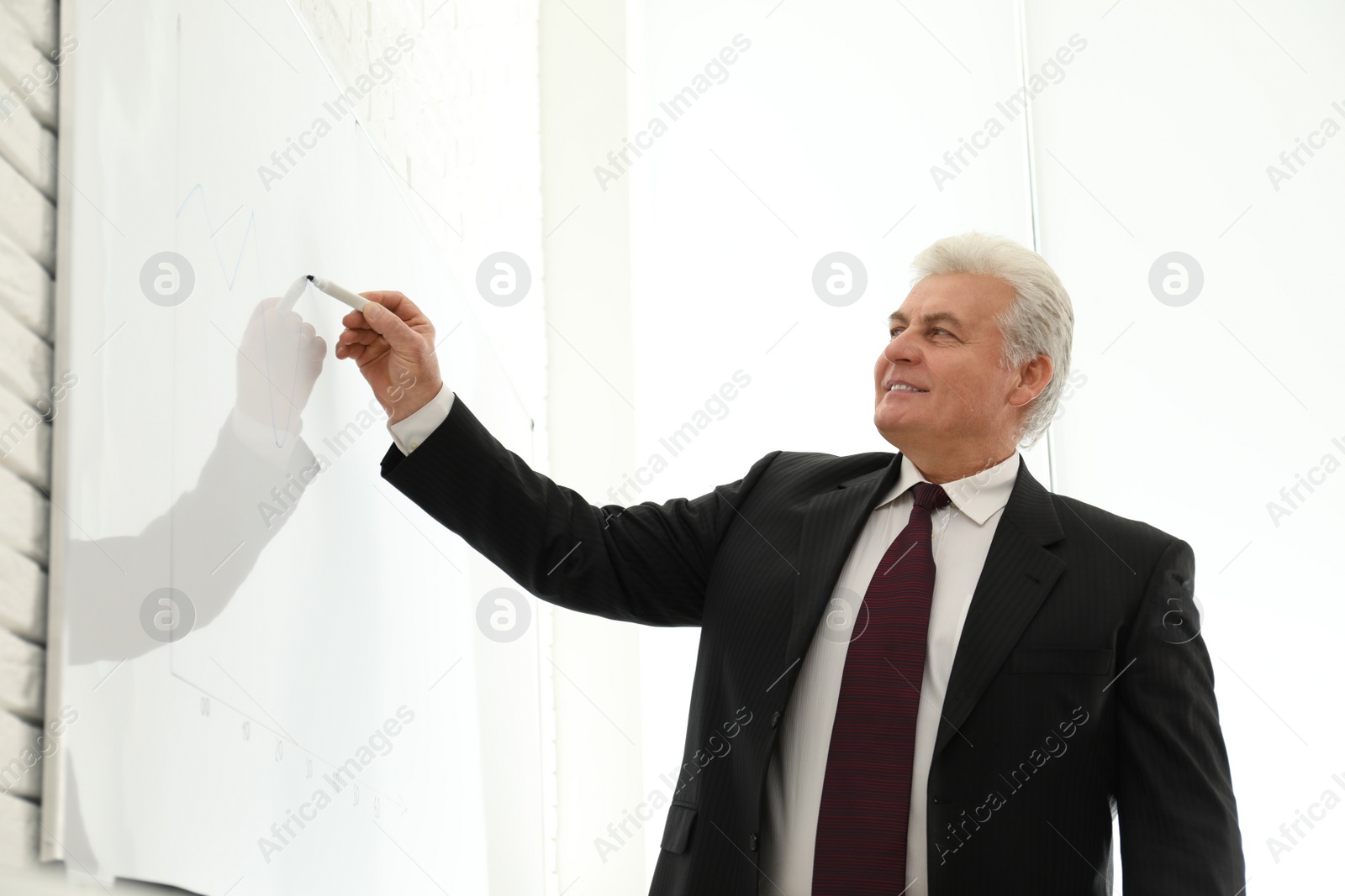 Photo of Senior business trainer near whiteboard in office