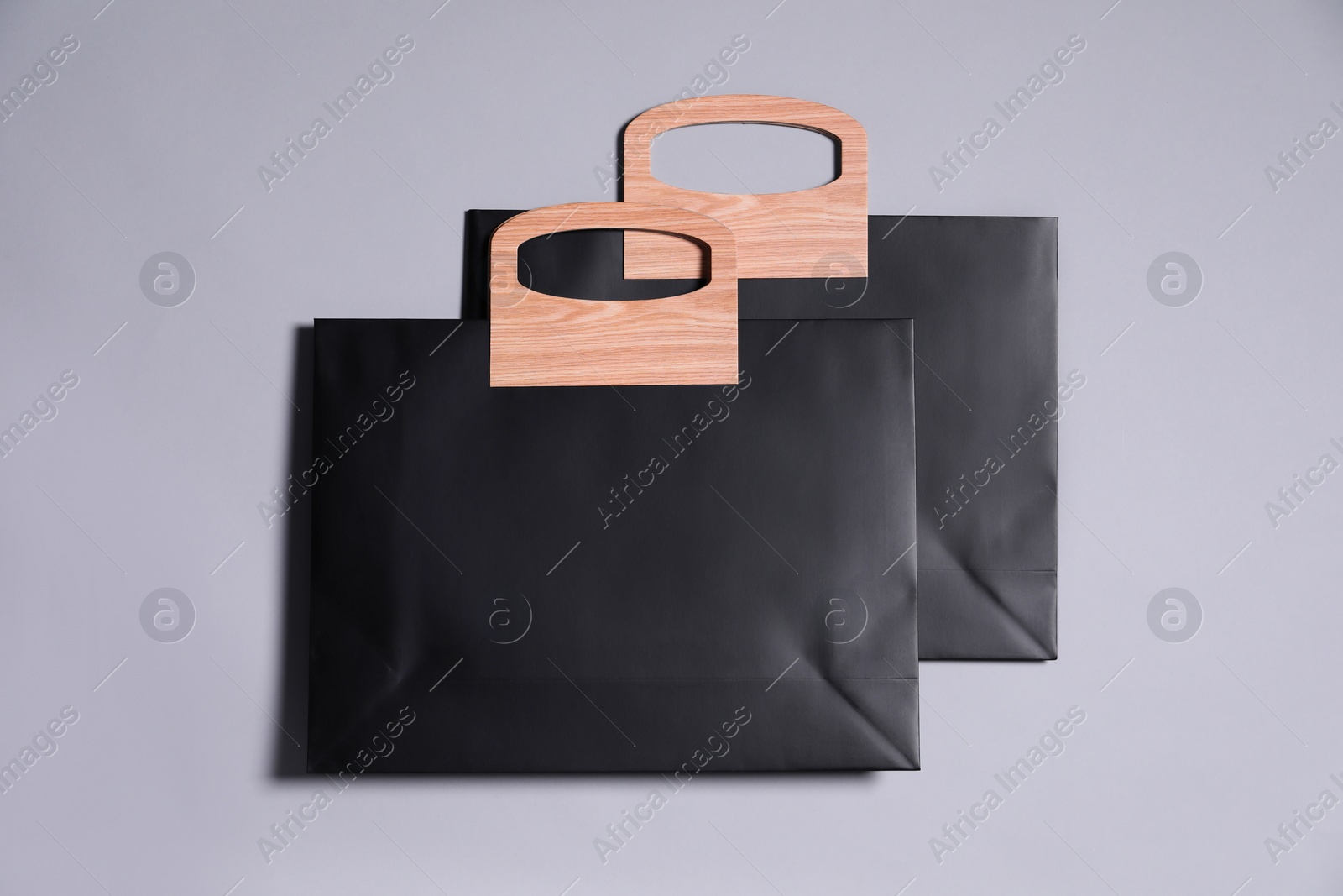 Photo of Two black paper shopping bags on grey background, top view