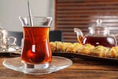 Photo of Traditional Turkish tea in glass and fresh baklava on wooden table, closeup