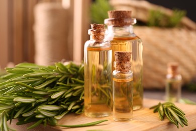 Photo of Essential oil in bottles and rosemary on table, closeup