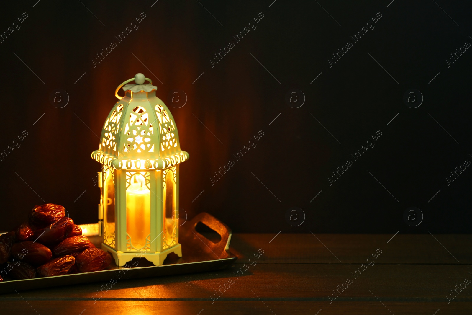 Photo of Decorative Arabic lantern and dates on table against dark background. Space for text