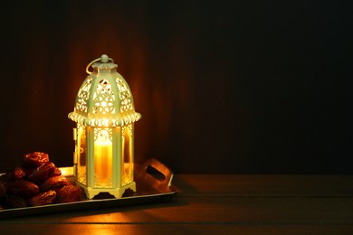 Photo of Decorative Arabic lantern and dates on table against dark background. Space for text