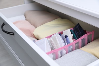 Open drawer with folded handkerchiefs and clothes indoors, closeup