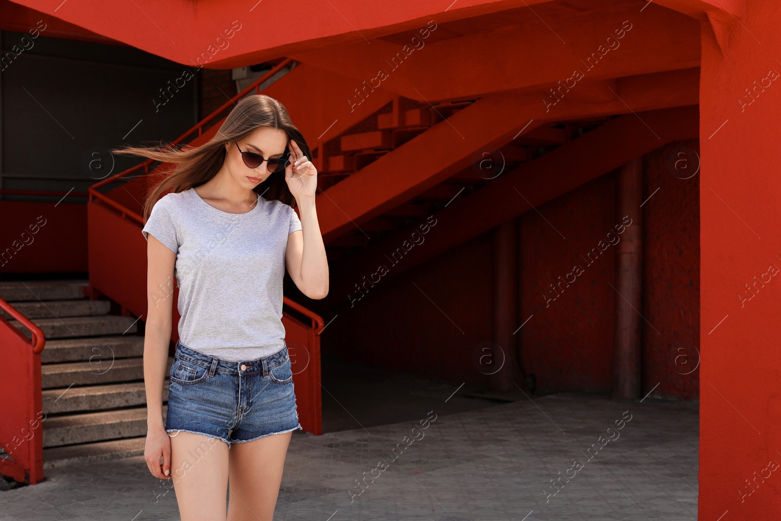 Photo of Young woman wearing gray t-shirt on street. Urban style