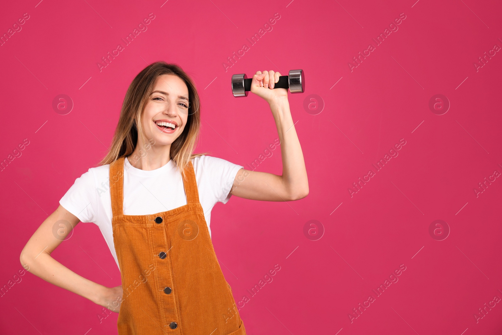 Photo of Woman with dumbbell as symbol of girl power on pink background, space for text. 8 March concept