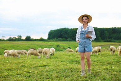 Photo of Smiling woman with tablet on pasture at farm. Space for text
