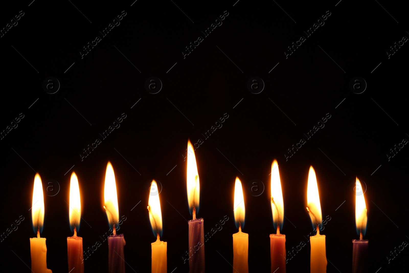 Photo of Hanukkah celebration. Burning candles on black background