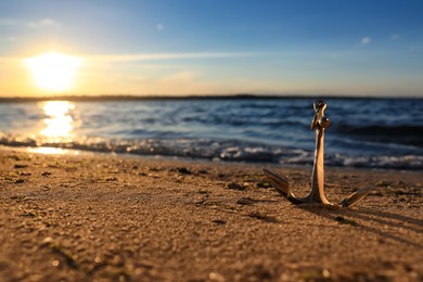 Photo of Metal anchor on shore near river at sunset