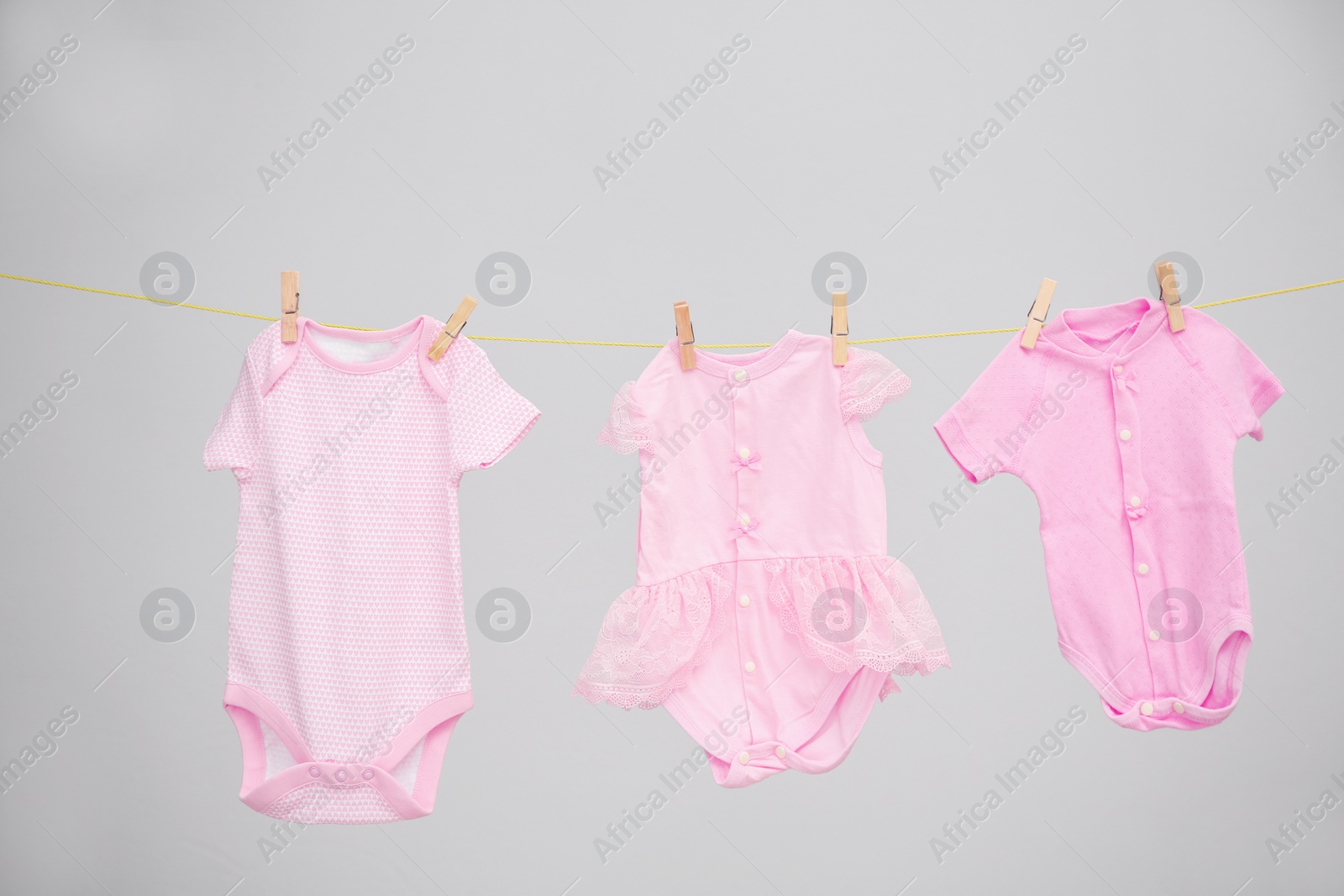 Photo of Baby clothes hanging on washing line against gray background