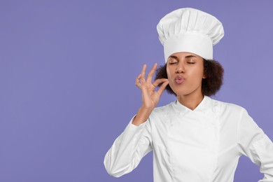 Photo of Happy female chef in uniform showing perfect sign on purple background. Space for text