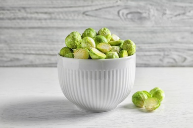 Photo of Bowl of fresh Brussels sprouts on table against wooden background