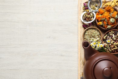 Photo of Clay teapot and different dried herbs on white wooden table, top view. Space for text