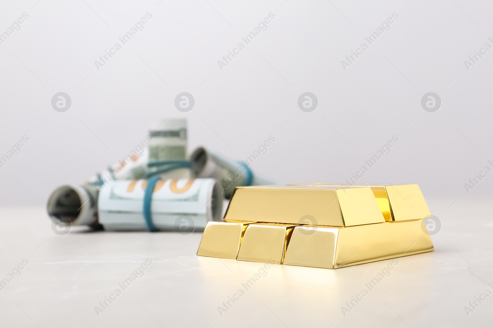 Photo of Shiny gold bars and dollar rolls on table. Space for text