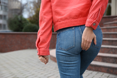 Woman suffering from hemorrhoid pain outdoors, closeup