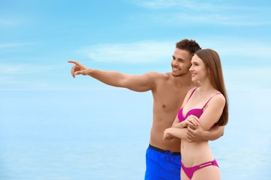 Young woman in bikini with her boyfriend on beach. Lovely couple