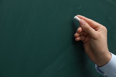 Teacher writing with chalk on green chalkboard, closeup. Space for text