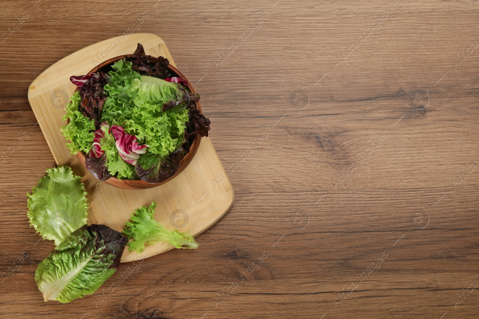 Photo of Different sorts of lettuce on wooden table, flat lay. Space for text