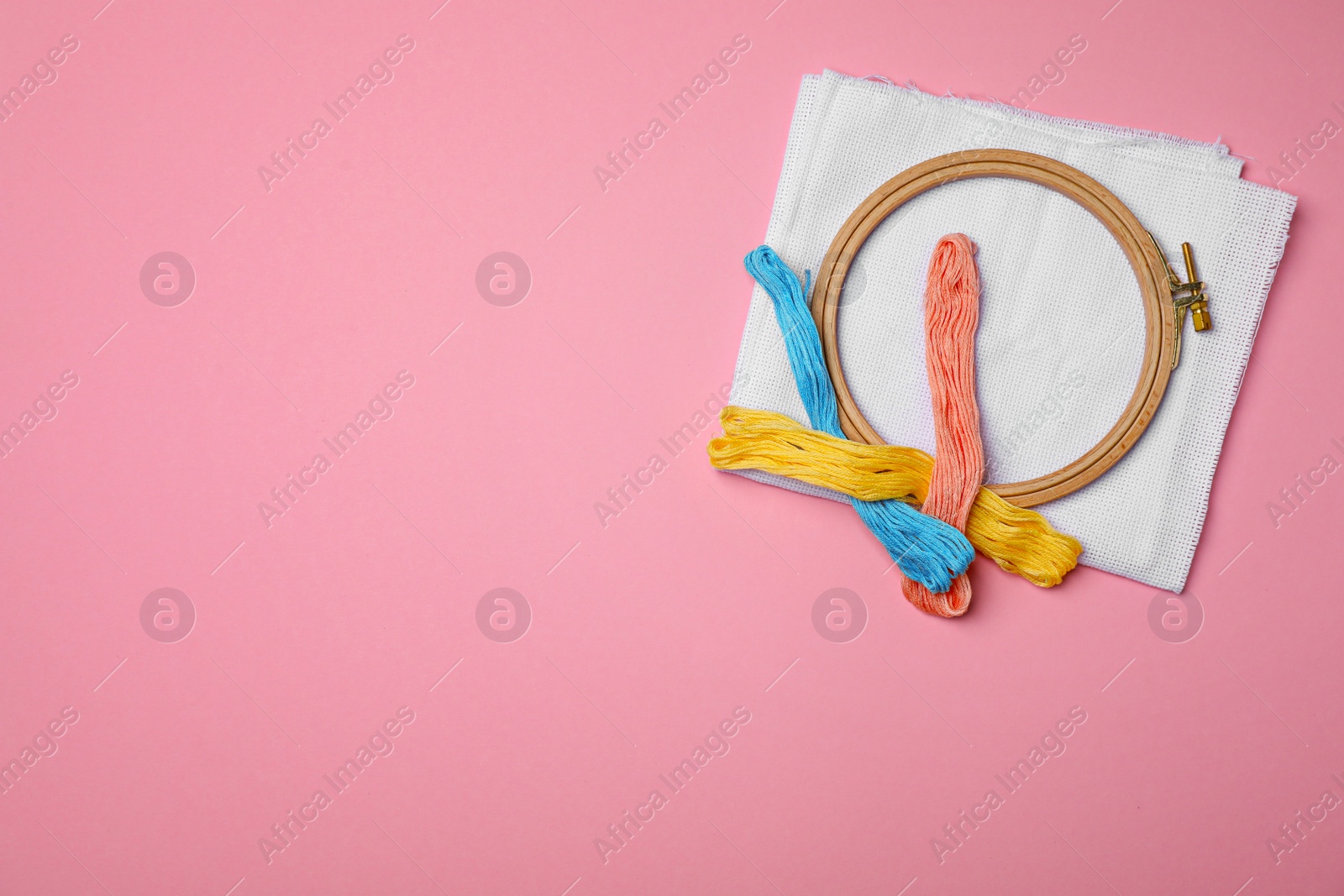 Photo of Sewing threads, fabric and hoop on color background