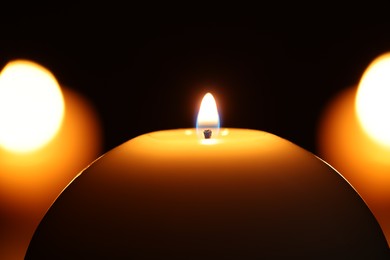 Burning wax candles on black background, closeup