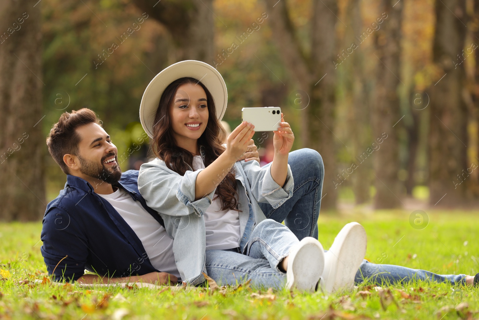 Photo of Beautiful young couple taking selfie in park. Space for text