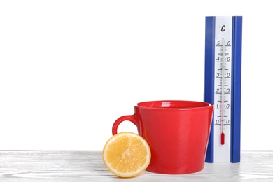 Photo of Thermometer, lemon and cup of hot tea on wooden table against white background. Space for text