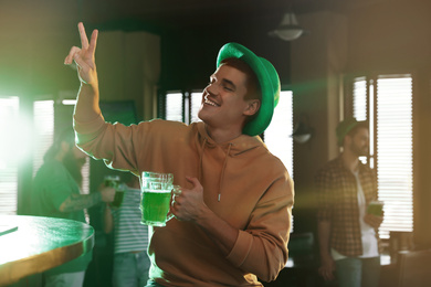 Photo of Happy man with glass of green beer in pub. St. Patrick's Day celebration